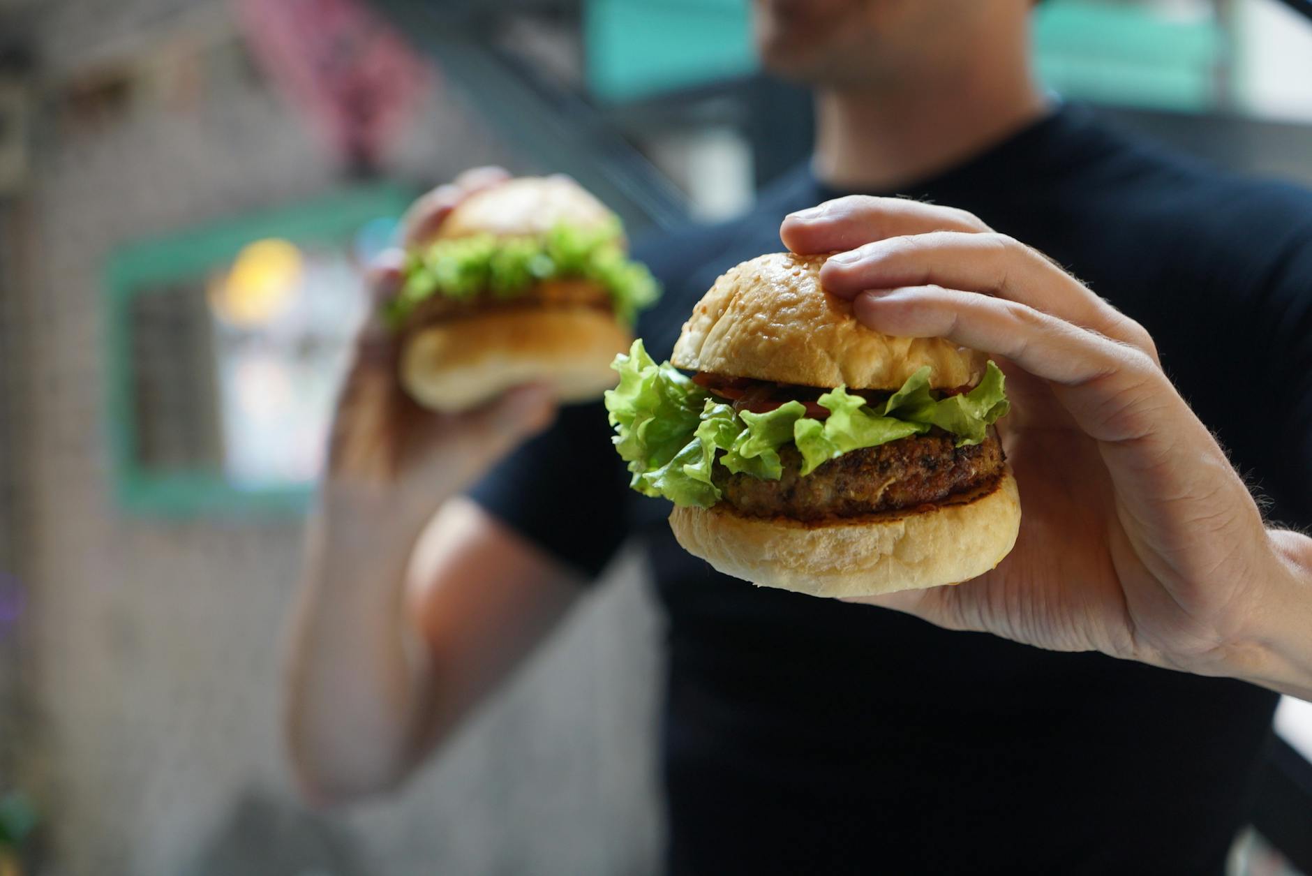 Dłoń trzyma domowego burgera z sałatą, zbliżenie idealne do przepisu Dłoń trzyma domowego burgera z sałatą, zbliżenie idealne do przepisu