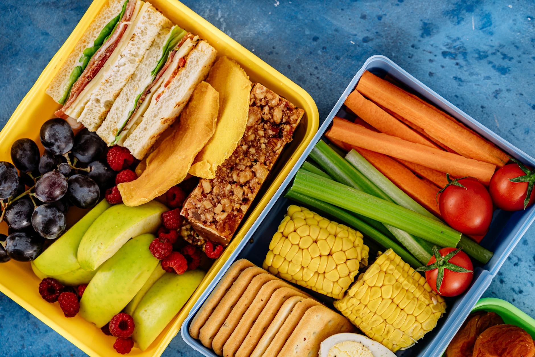 Lekkie obiady do pracy: szybkie fit przepisy na zdrowe lunchboxy Zdrowy lunchbox z kanapkami, warzywami i owocami widziany z góry